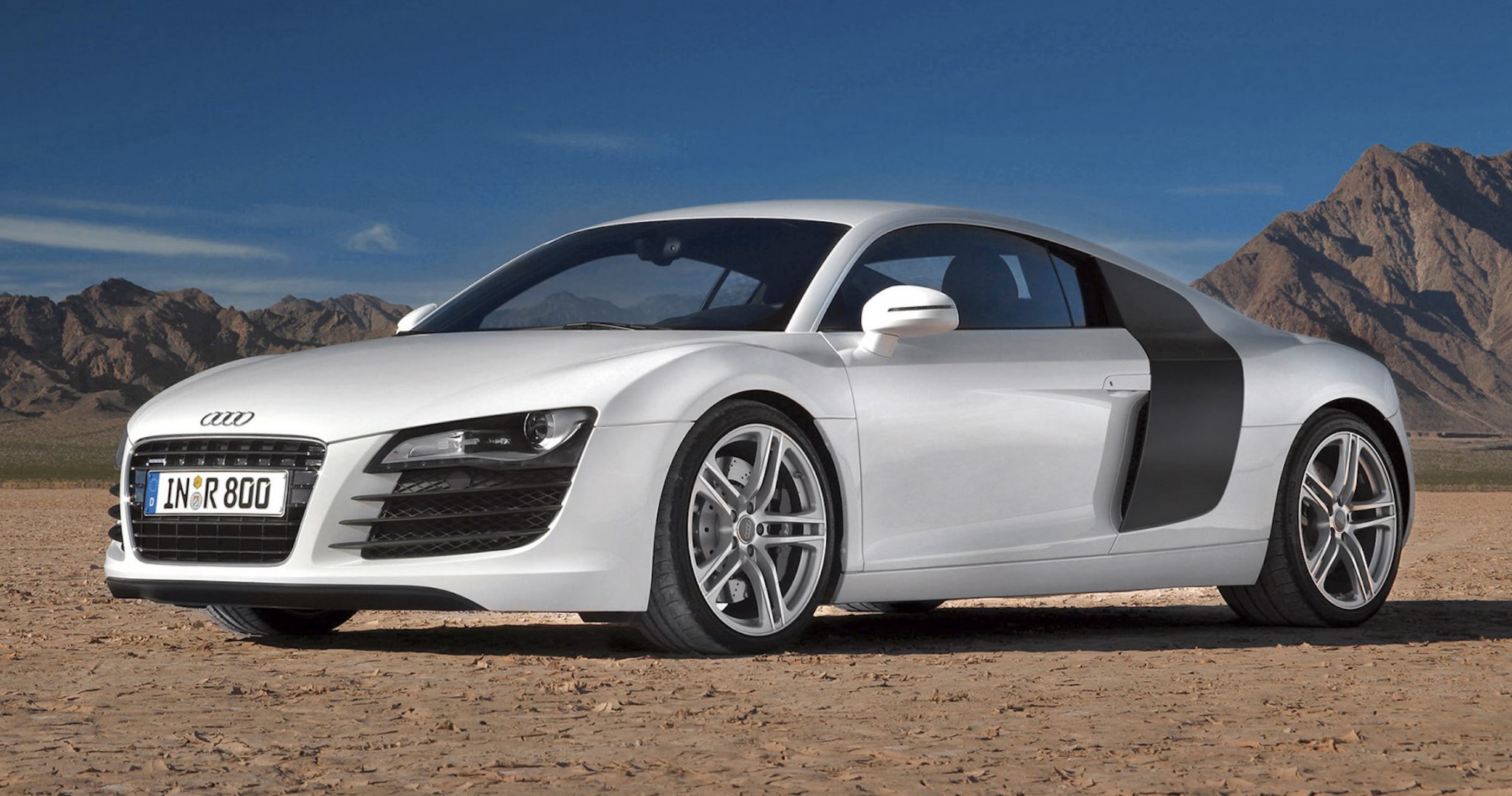 A side view of a white First Gen Audi R8 in a desert