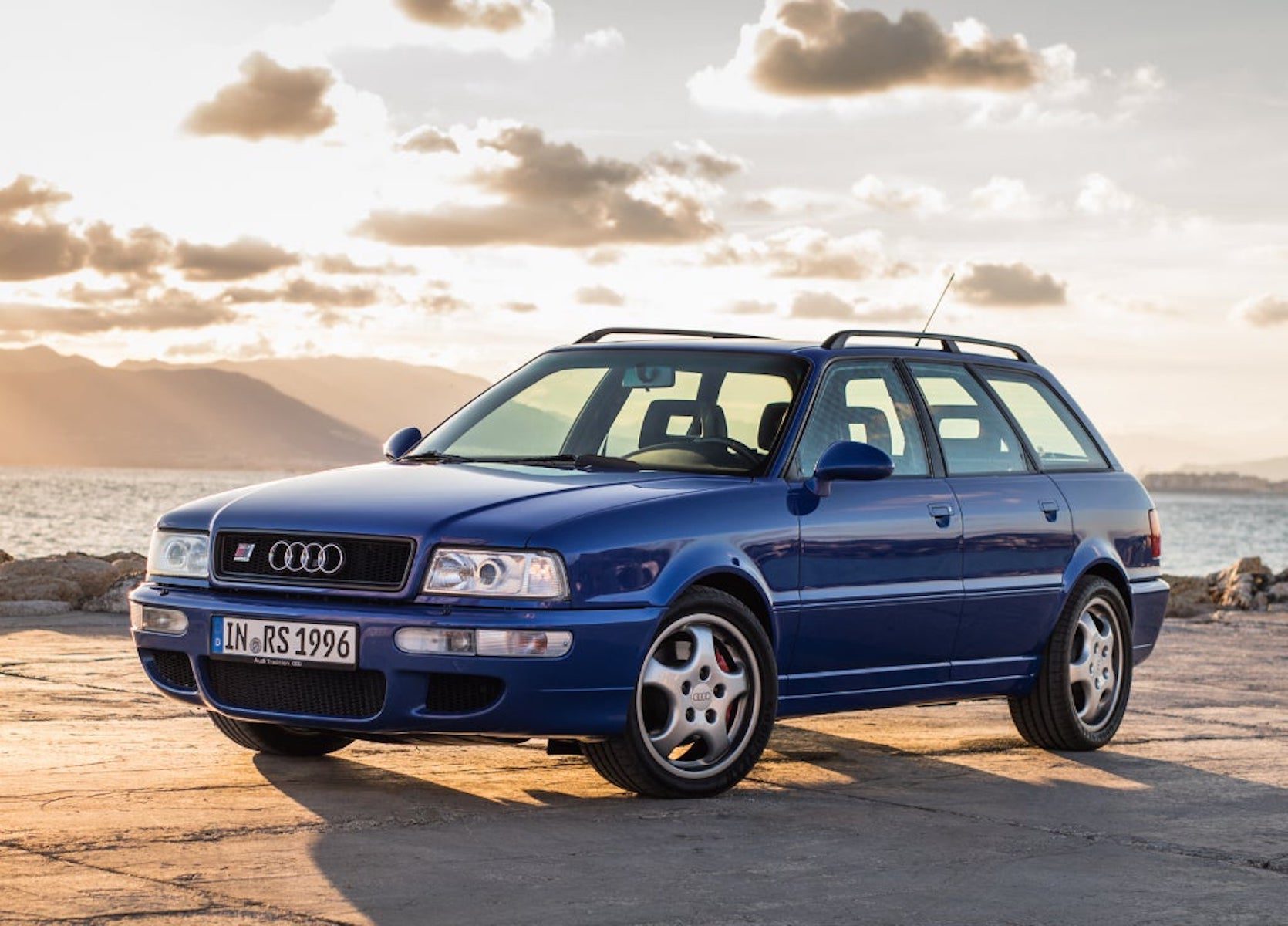 A side view of a blue 1994 Audi RS2 Avant Station Wagon in front of a lake