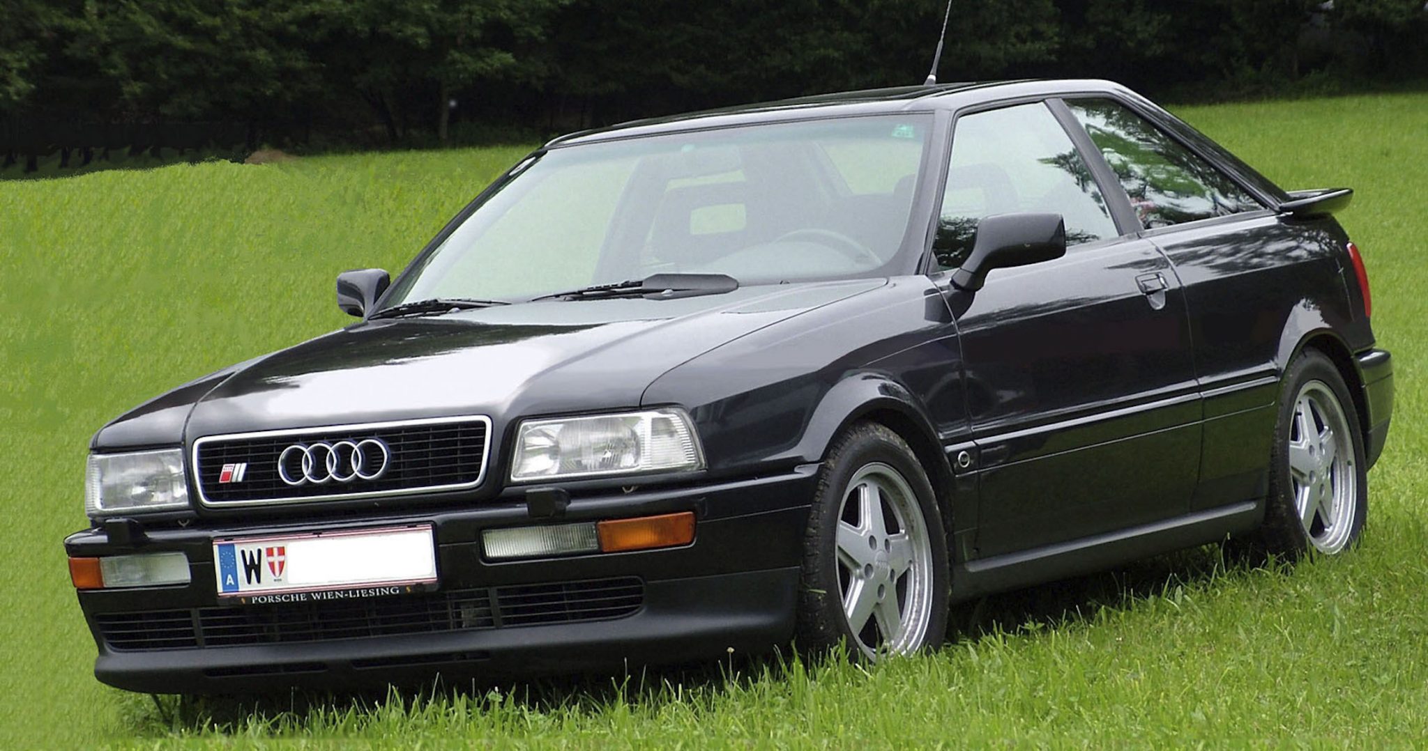 A side view of a black 1990 Audi S2 Coupe parked in the grass