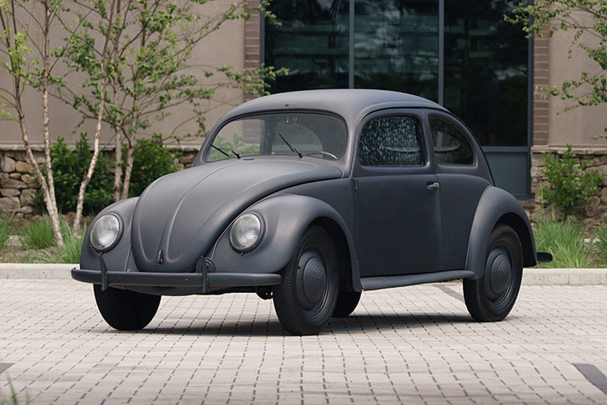 A side view of a 1943 matte black VW Beetle in a parking lot