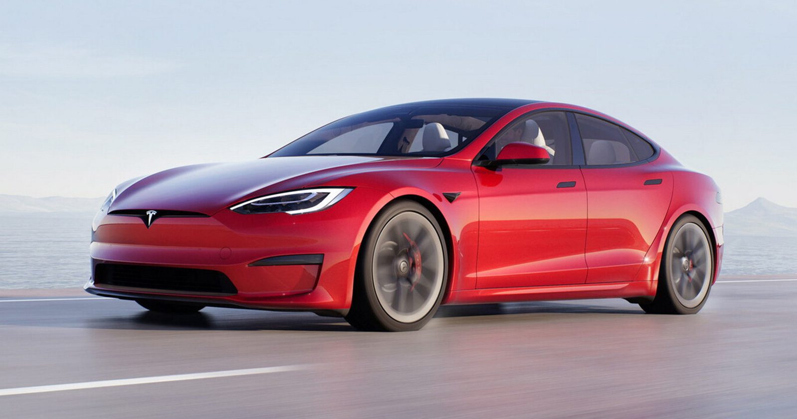 2022 red Tesla Model 3 cruising down a road