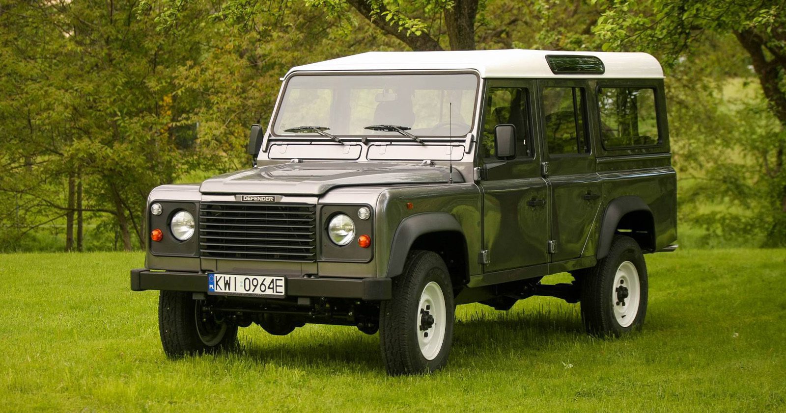 1994 military green Land Rover Defender 110 on countryside