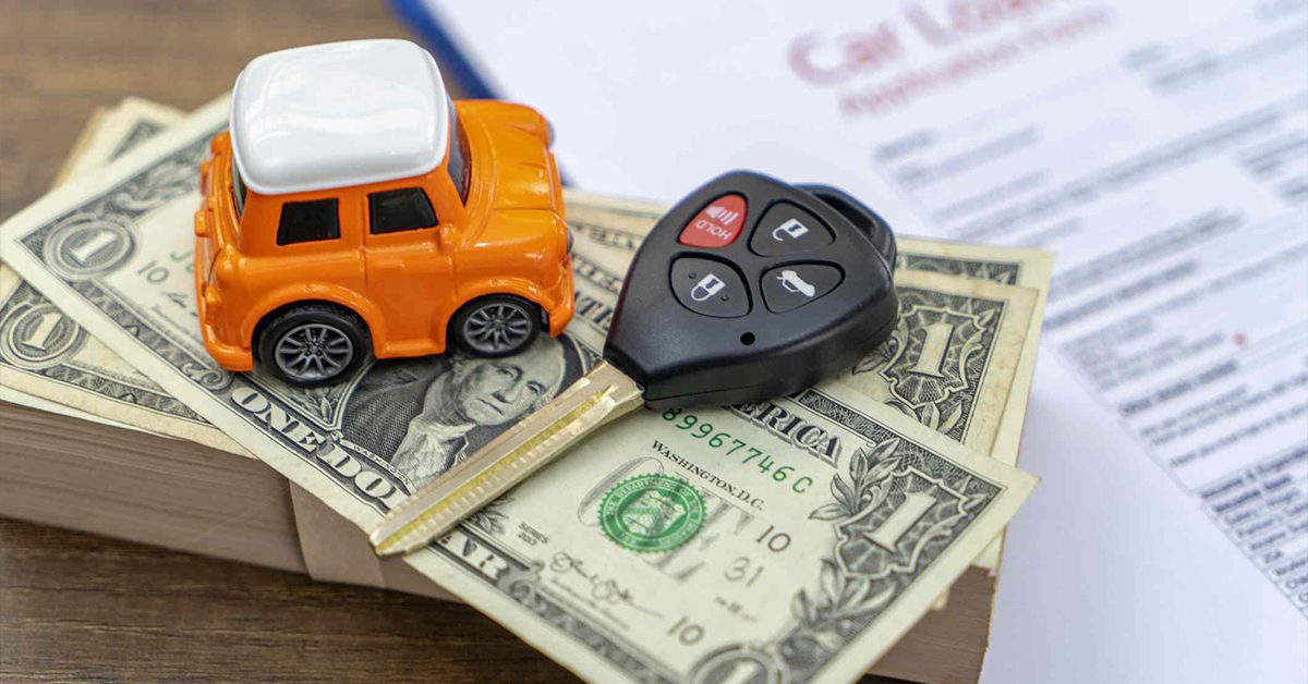 Toy car and a car key on top of a stack of dollars