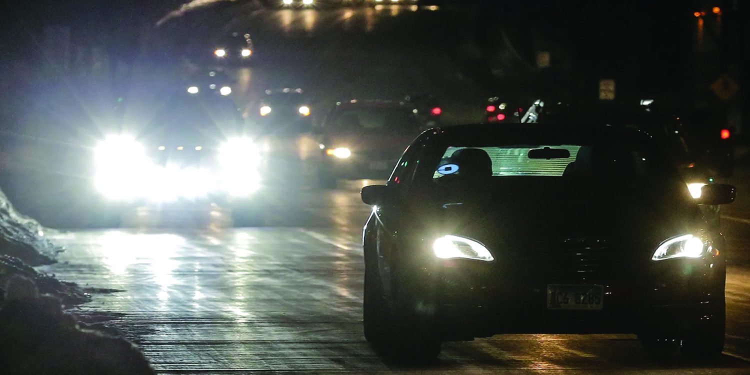 Drivers at night on city streets with bright headlights