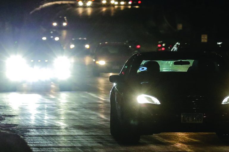 Drivers at night on city streets with bright headlights