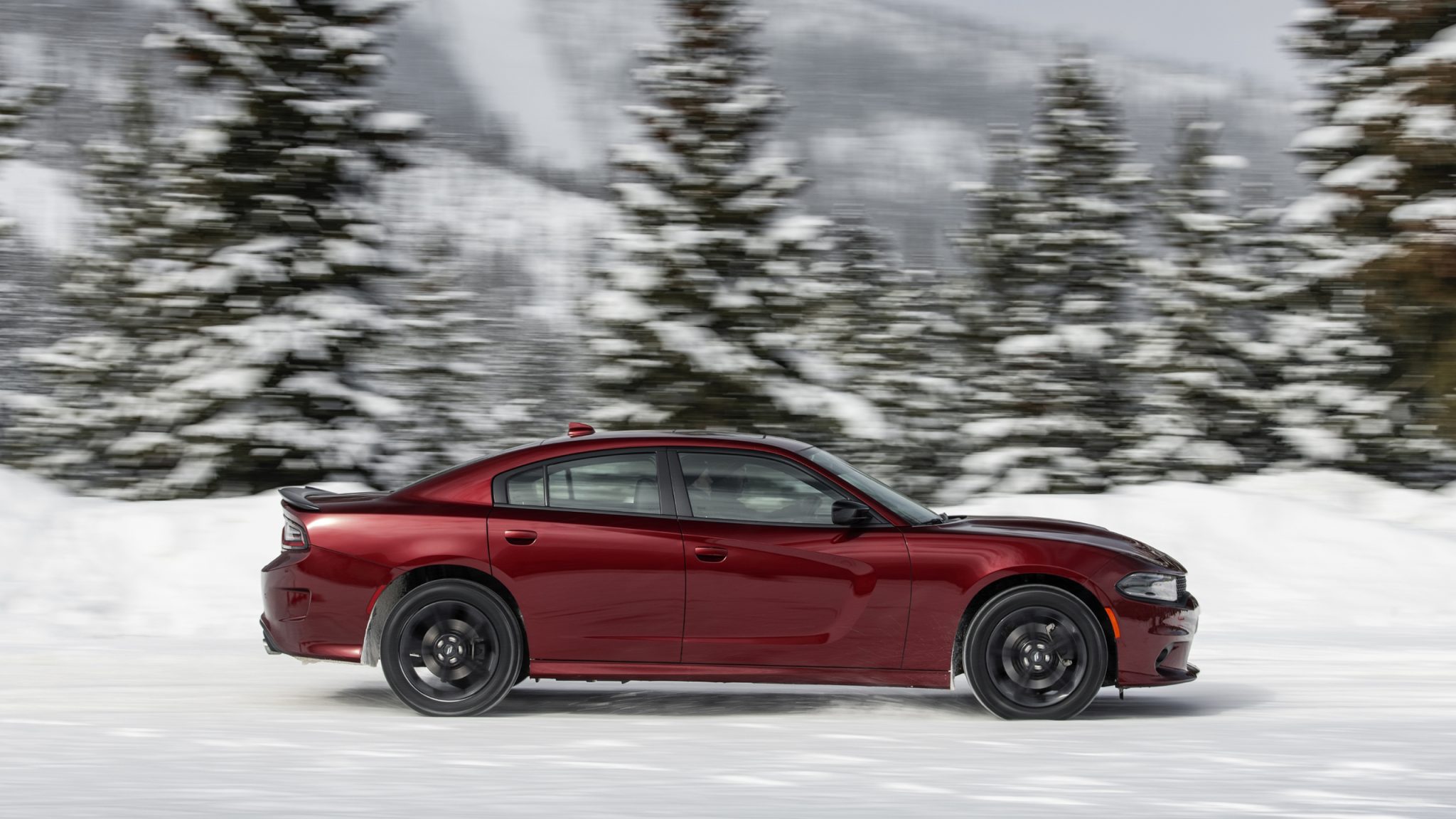 Side view of a 2023 red Dodge Charger GT driving in the snow