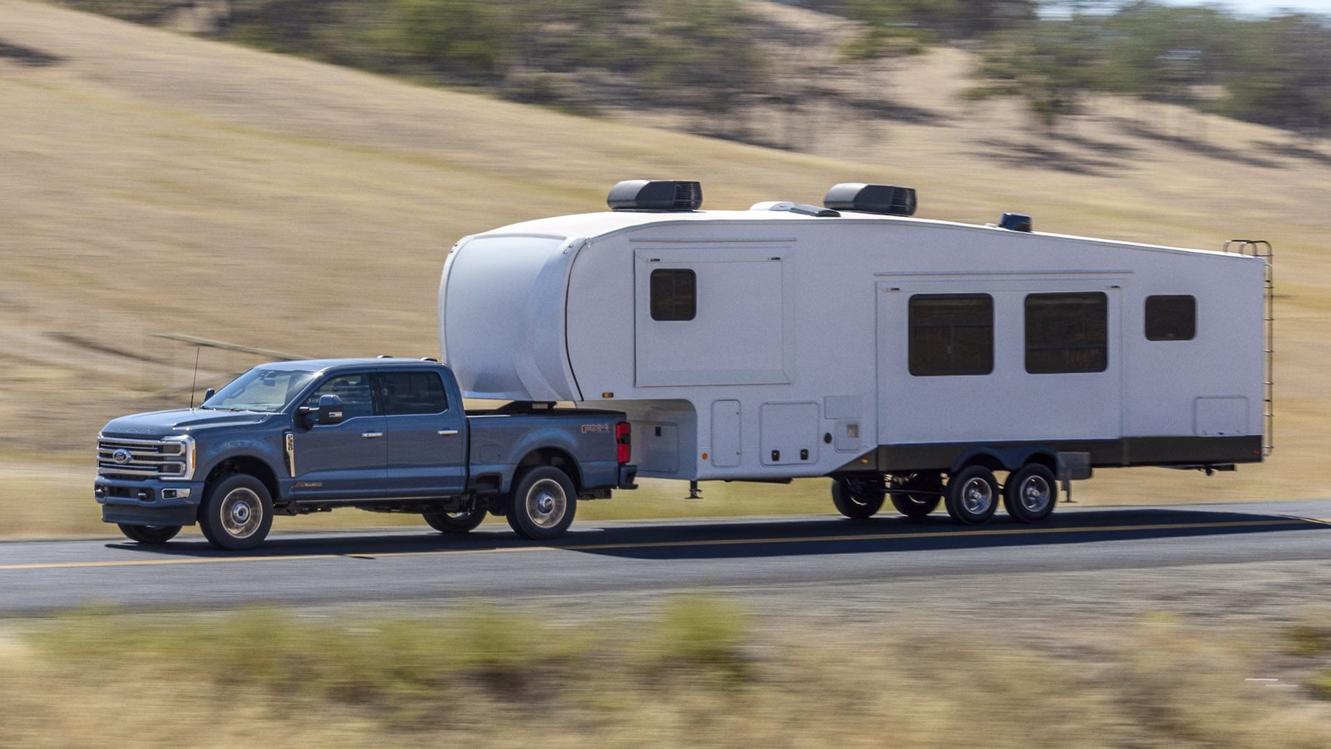 Side view of a 2023 blue Ford F-250 Super Duty pulling a trailer