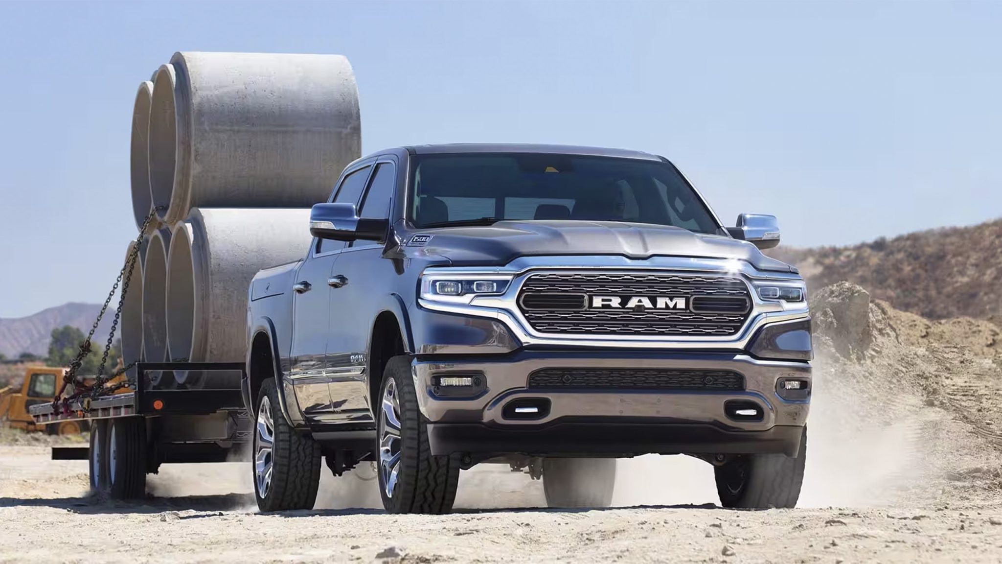 Front view of a 2023 grey Ram 1500 towing a heavy load