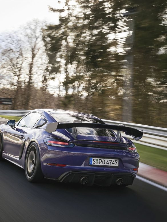Rear view of a 2023 Purple Porsche 718 Cayman GT4 RS on a track
