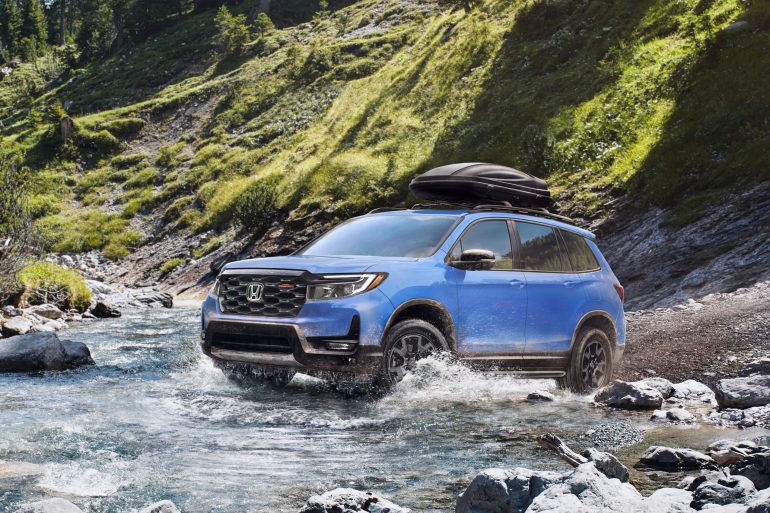 Three-quater view of a 2024 blue Honda Passport Trailsport crossing a river