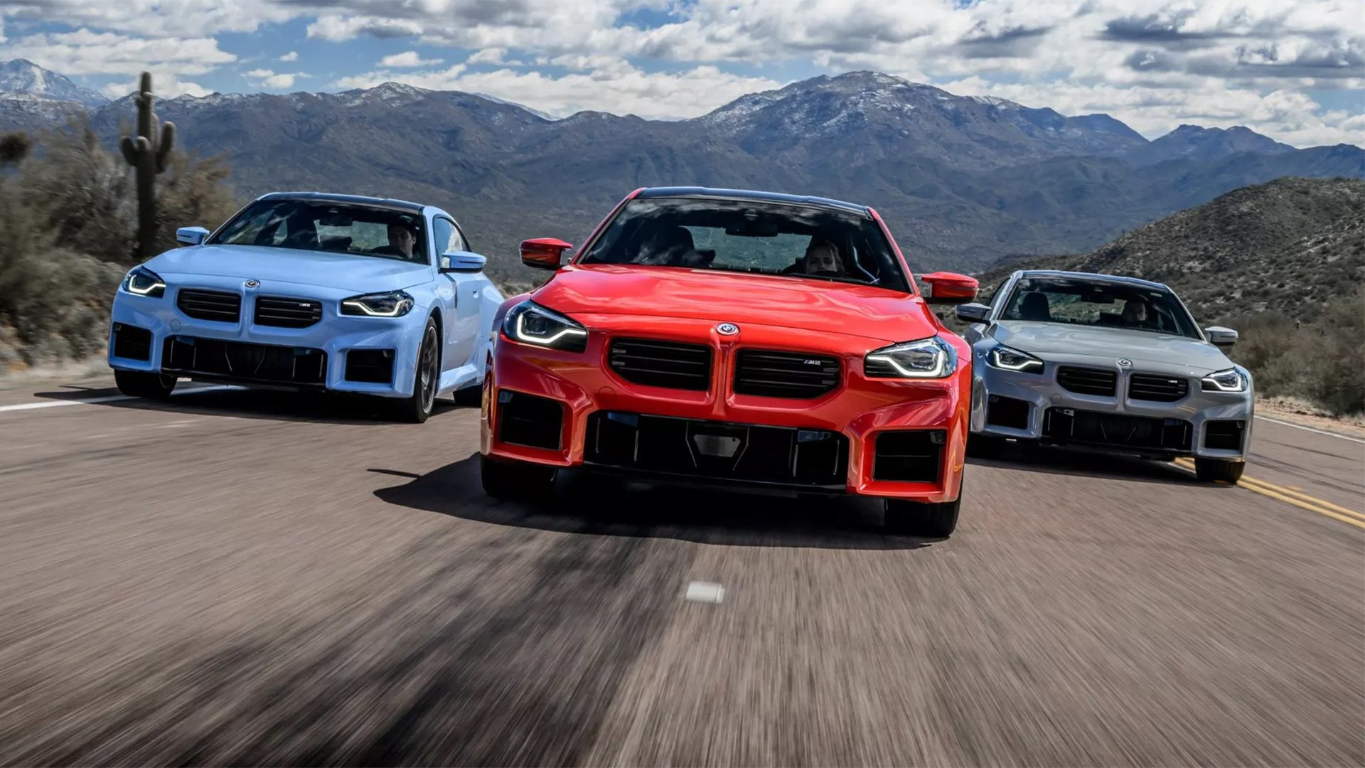 Frontal view of three 2024 BMW M2 coupes driving on a highway