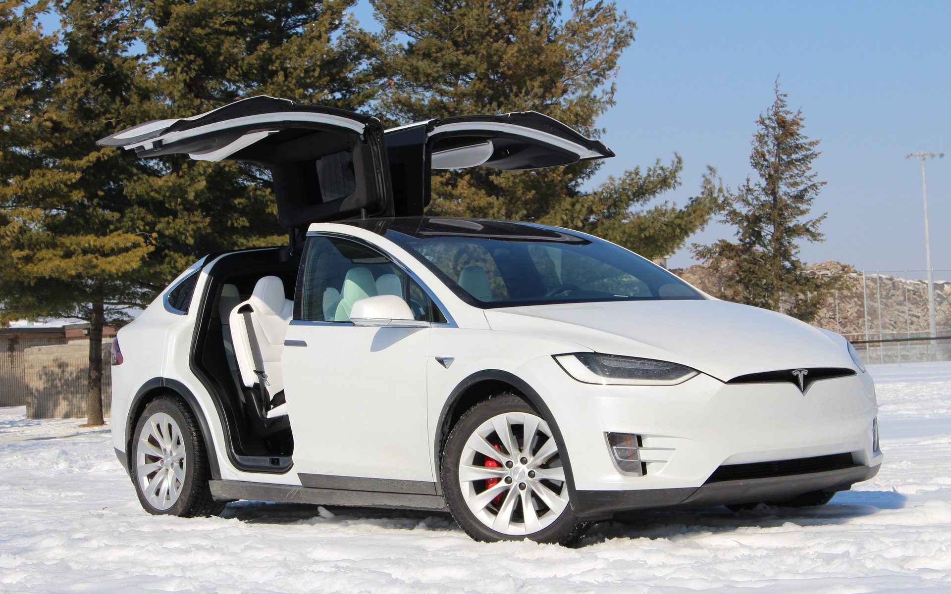 Front-angled view of a white Tesla Model X with doors open