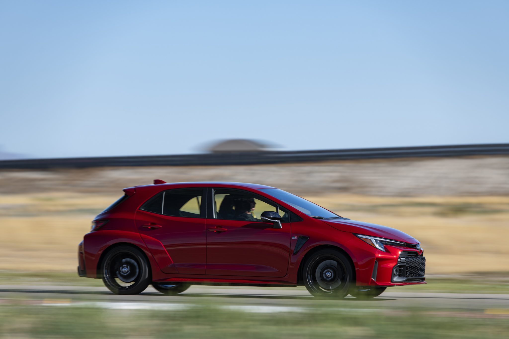 Side view of a 2024 red Toyota GR Corolla at high speed