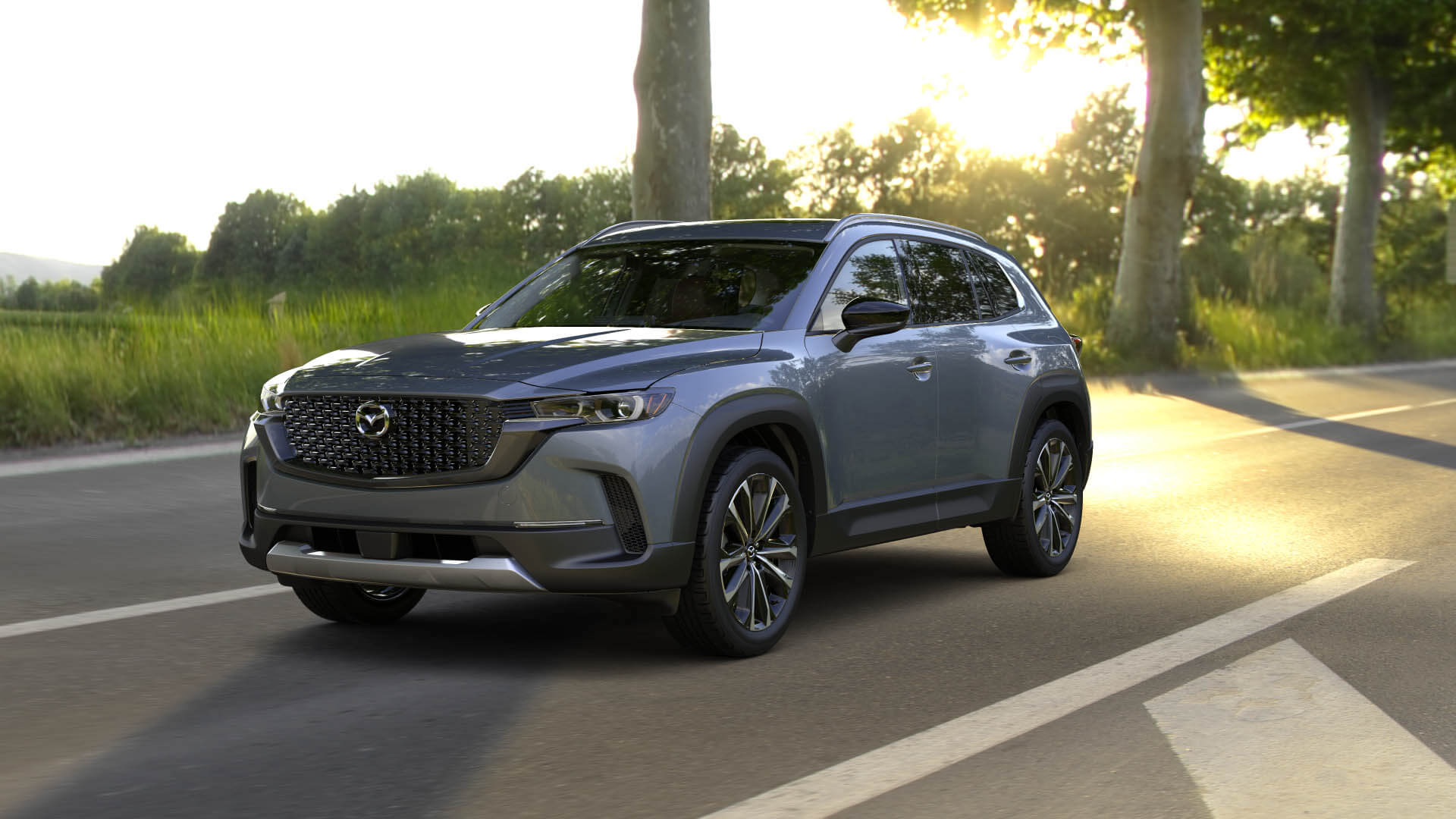 Three-quarter front view of a 2024 grey Mazda CX-50 with sunset background