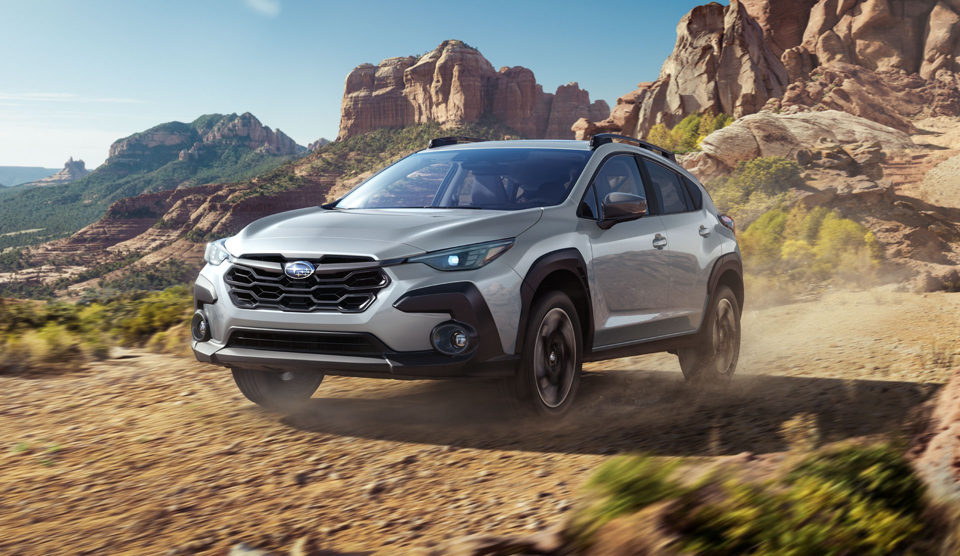 Three-quarter front view of a 2024 silver Subaru Crosstrek on a trail road
