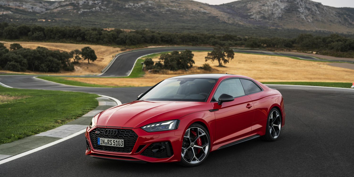 Three-quarter side view of a 2024 red Audi RS5 Sportback on a track