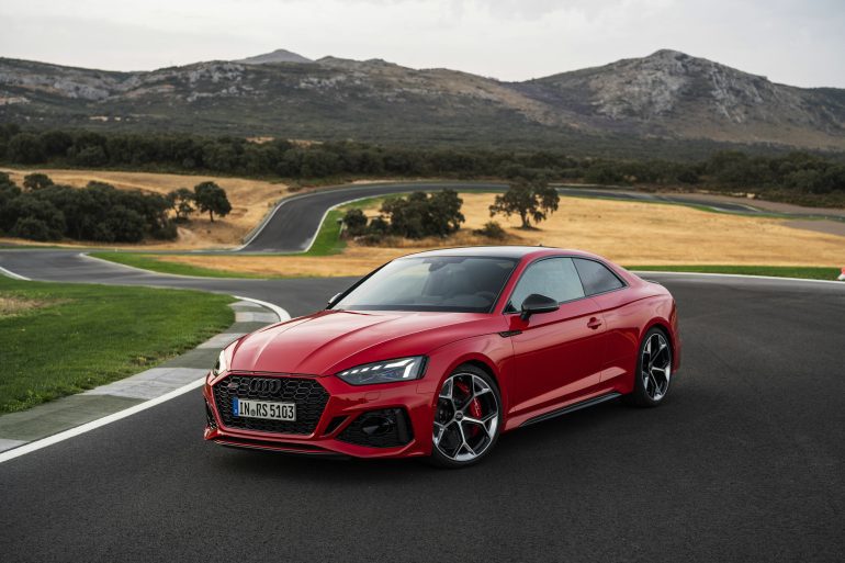Three-quarter side view of a 2024 red Audi RS5 Sportback on a track