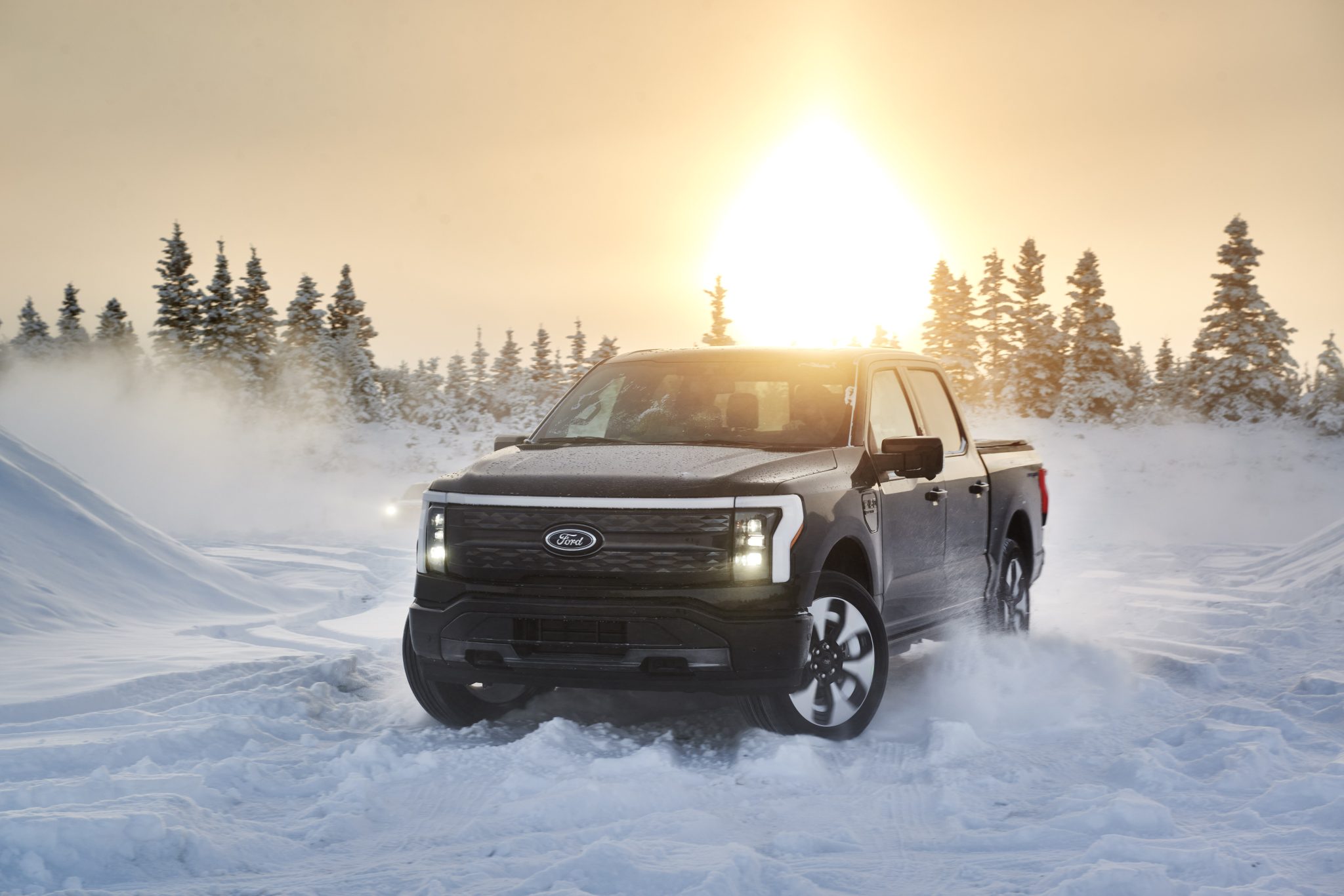 Front view of a 2024 black Ford F-150 Lightning driving on snow