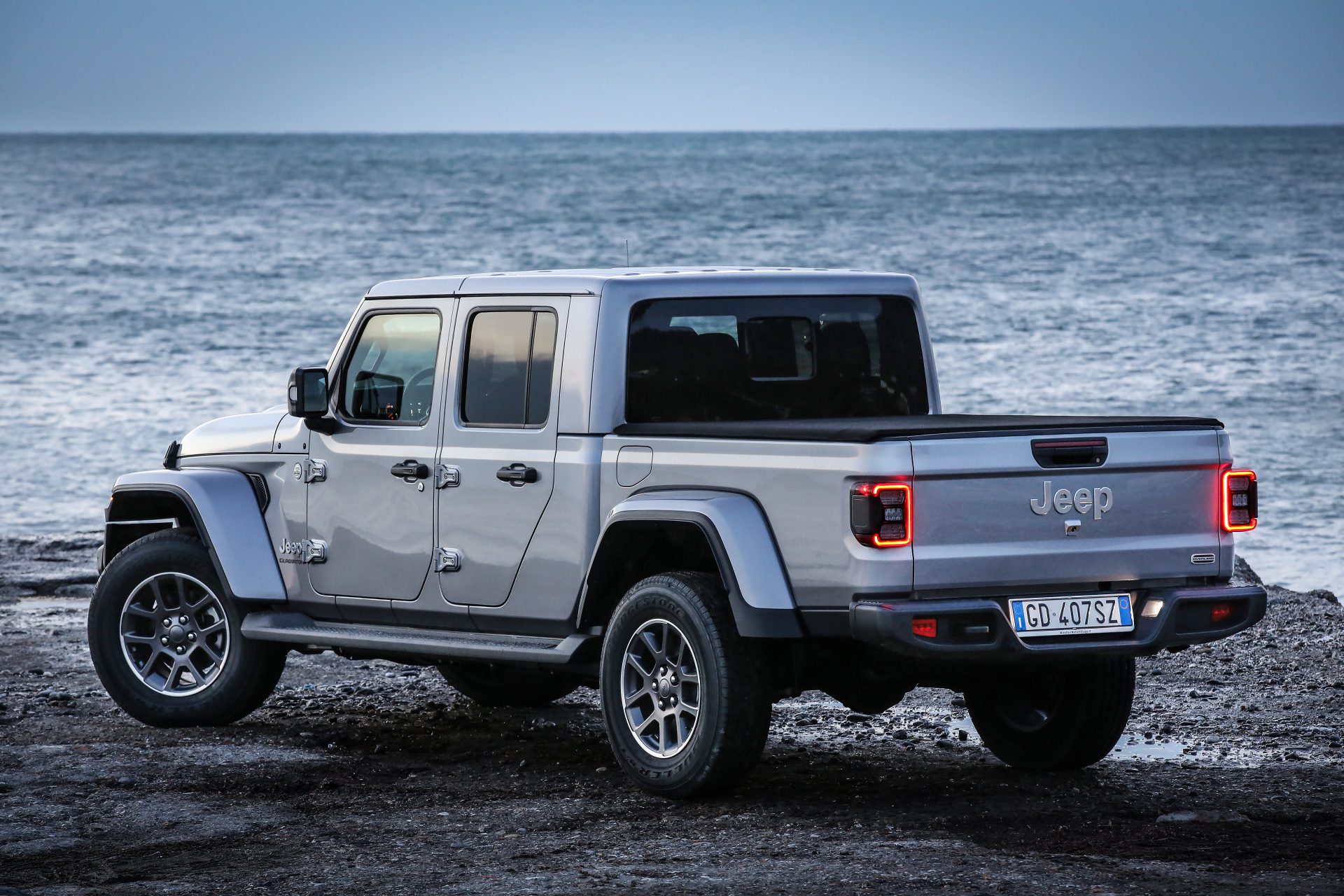 3/4 rear view of a 2024 silver Jeep Gladiator on a beach