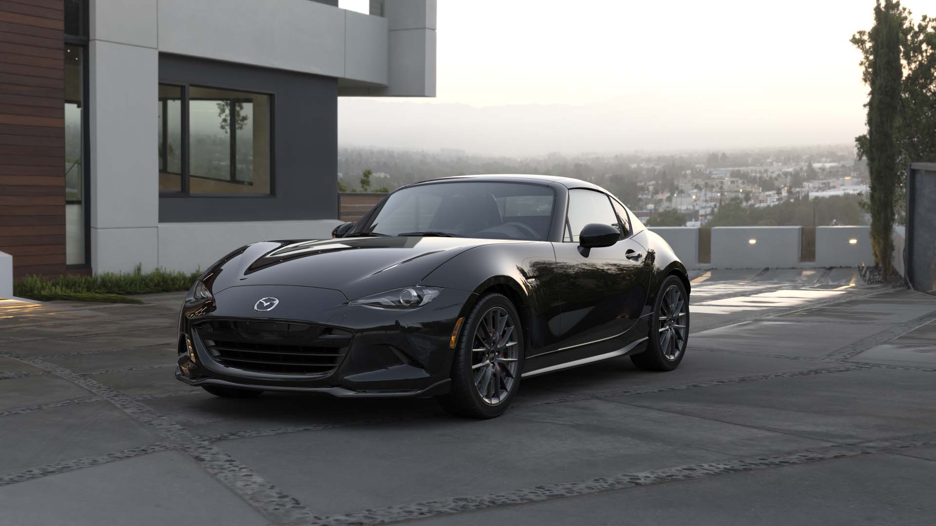 Front view of a 2024 black Mazda Miata RF with city background