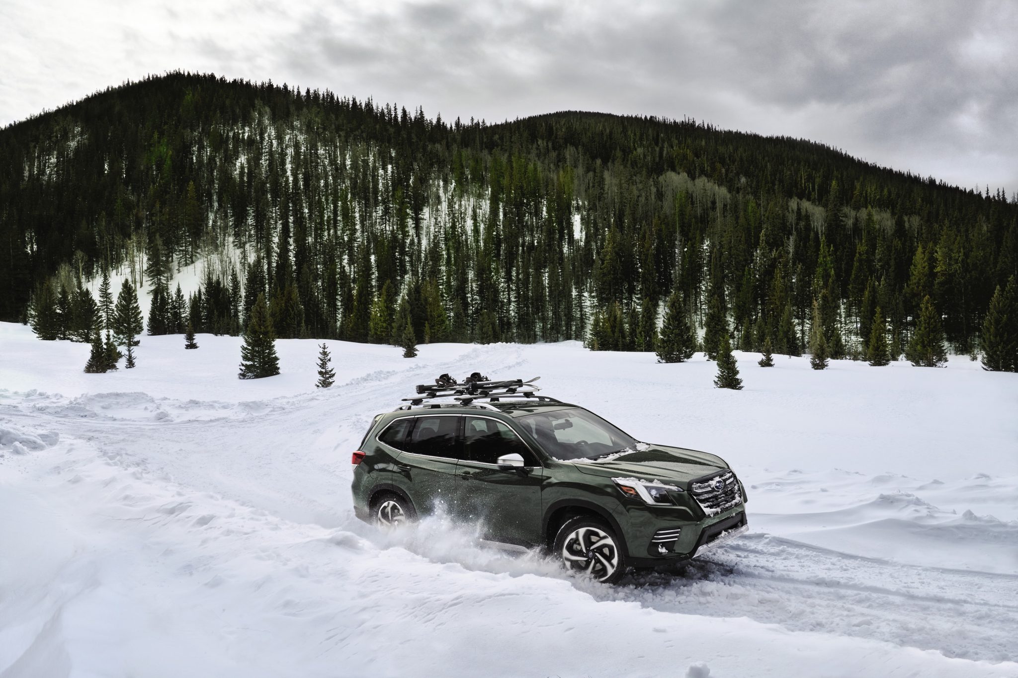 Side view of a 2024 green Subaru Forester driving on snow