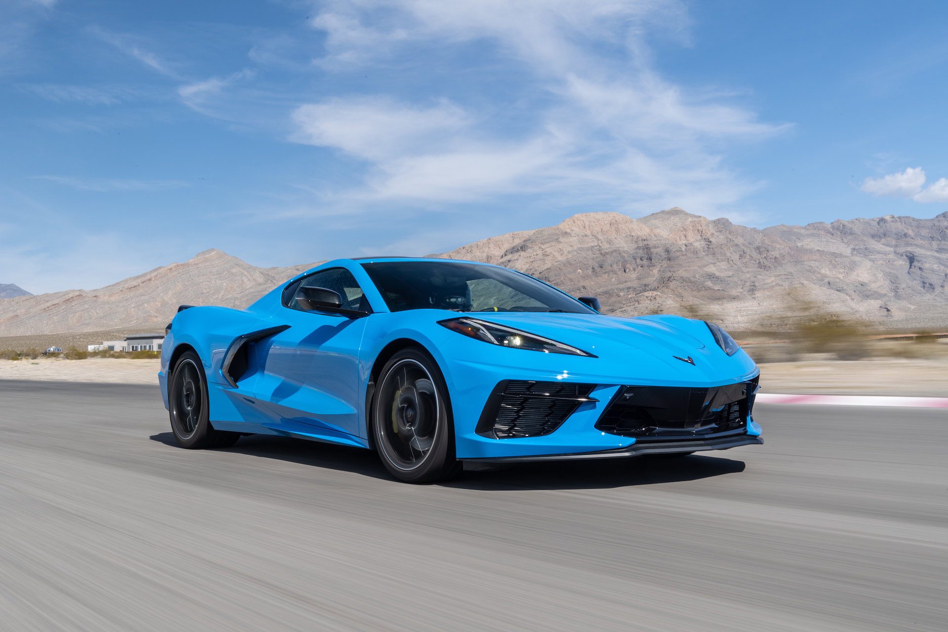Front-angled view of a blue Chevrolet C8 Corvette driving along a highway