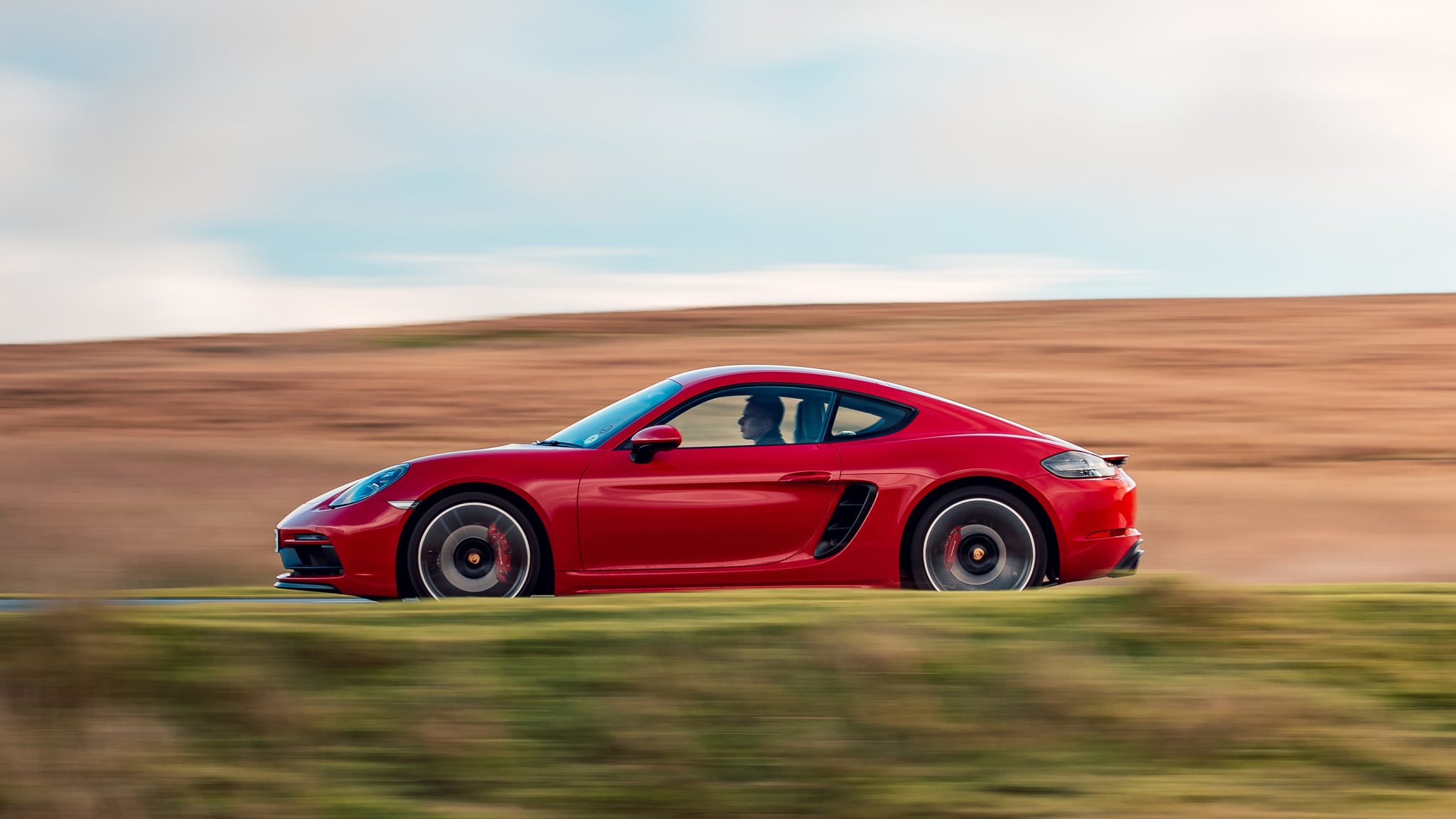 Side profile of a red Porsche 718 Cayman coupe